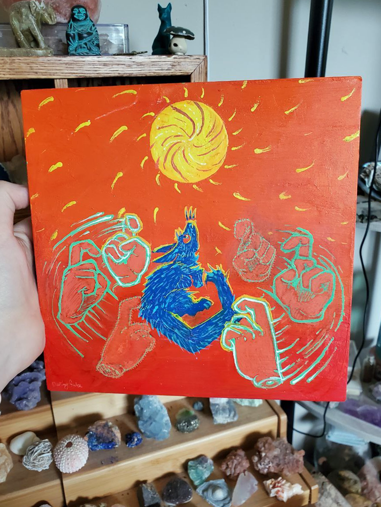 Painting of a unknown furry blue creature with abstract designs on an orange background, with a spinning sun above the creative, and the outlined glowing with motion color loss signing hands for "CHANGE" around the blue creature, and the painting is held in front of a display of crystals.